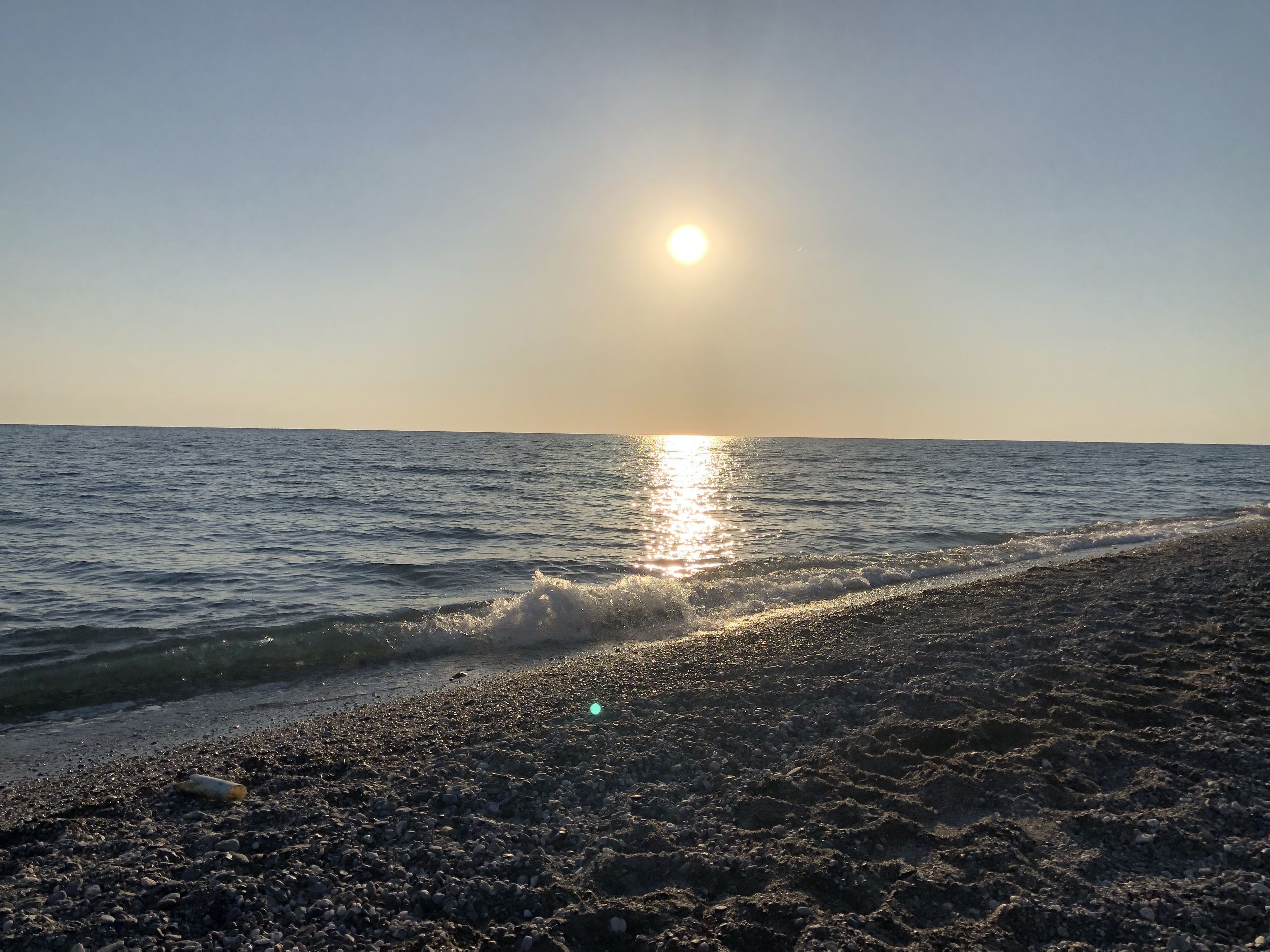 Ein Strand mit Kieselsteinen und blauem Himmel.