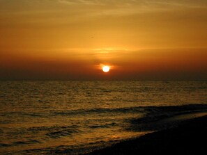 A sunset over a body of water with a beach in the foreground. - Residence Mareblu (Nocera Terinese)