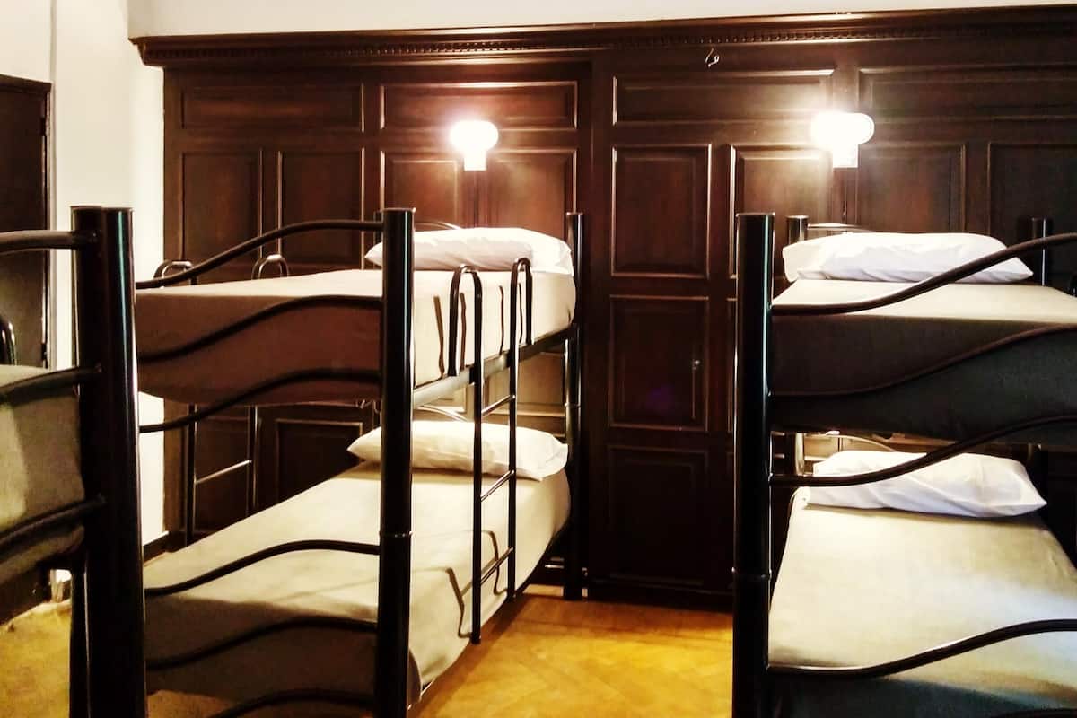 A room with bunk beds, wooden headboard, and a chandelier.