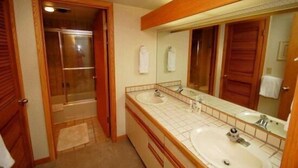 Een badkamer met twee wasbakken, een grote spiegel en een douchehoek.