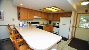 A kitchen with wooden cabinets, a white countertop, and a built-in stove.