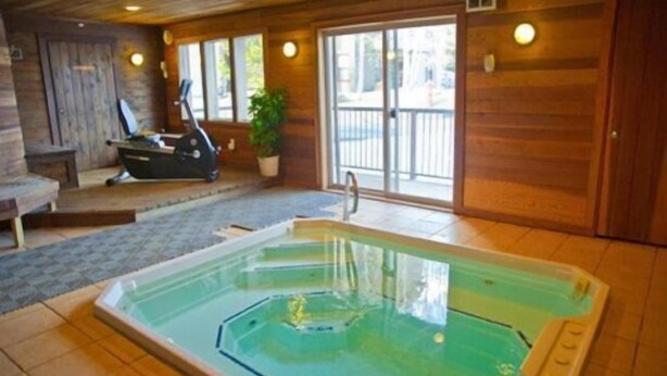 A spa area with a hot tub, exercise equipment, and a view of the outside.