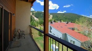 A balcony with a view of a mountainous landscape and a house with a red roof.