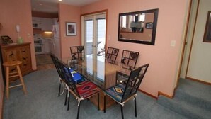A dining area with a glass-top table and chairs, a kitchen in the background, and a mirror on the wall. - Red Fox Town home 3 Bedroom Apartment by Key to the Rockies (Dillon)