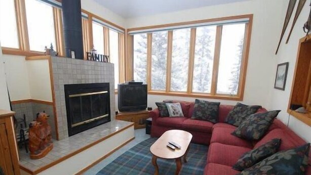A cozy living room with a fireplace, a red sofa, and a television. - Red Fox Town home 3 Bedroom Apartment by Key to the Rockies (Dillon)
