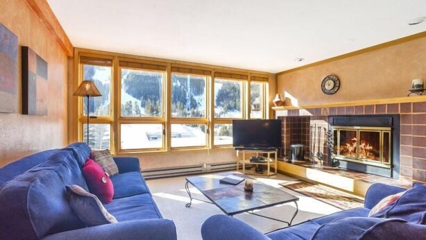 Ein Wohnzimmer mit Kamin, großen Fenstern und einer Couch.