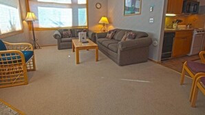 A living room with two sofas, a coffee table, and a dining area with a kitchen. - River Bank Lodge 1 Bedroom Apartment by Key to the Rockies (Keystone)