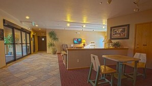 A lobby with a reception desk, a television, a potted plant, and a seating area with a table and chairs. - River Bank Lodge 1 Bedroom Apartment by Key to the Rockies (Keystone)