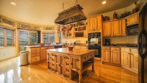 A spacious kitchen with wooden cabinets, a large island, and hanging pots. - Retreat at Summerwood 5 Bedroom Apartment by Key to the Rockies (Dillon)