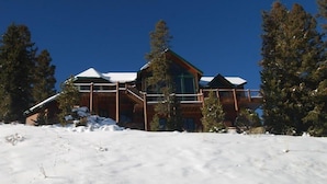 A large lodge with a prominent wooden structure, multiple balconies, and a snow-covered landscape. - Retreat at Summerwood 5 Bedroom Apartment by Key to the Rockies (Dillon)