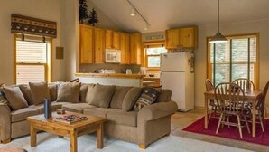 A cozy living room with a sofa, coffee table, and dining area with chairs and a table. - Snake River Village 3 Bedroom Apartment by Key to the Rockies (Keystone)