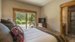 Un dormitorio con una cama grande, televisor y puerta corrediza que da a un balcón.