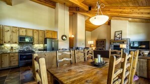 Una cocina rústica con armarios de madera, un salpicadero de piedra y una gran mesa de comedor de madera con sillas.