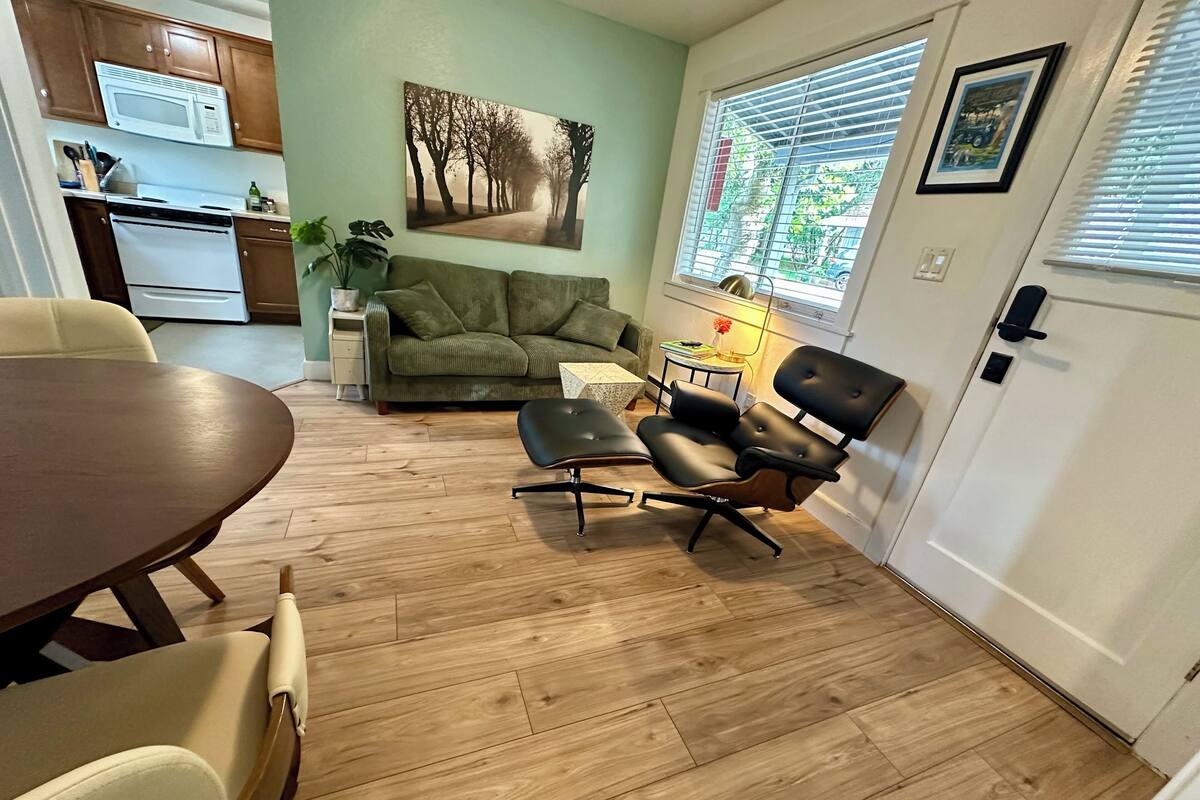 A modern living room with a dining area, a sofa, a coffee table, and a kitchen in the background.