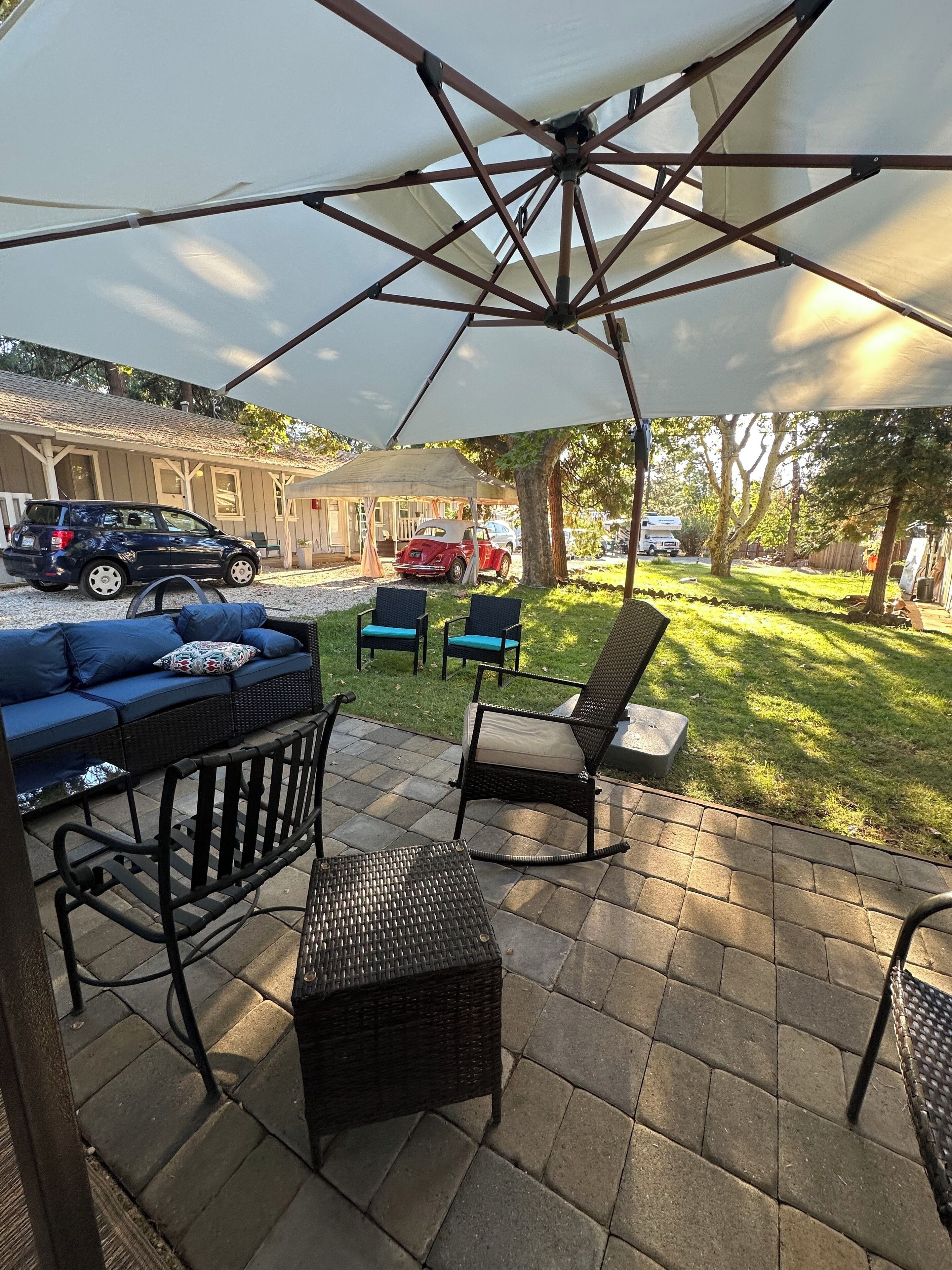An outdoor patio area with a covered seating area, including a sofa and chairs, and a table.