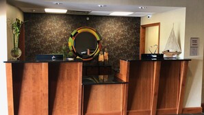 Una zona de recepción con un mostrador de madera, un espejo grande y una pared decorativa con motivos florales.