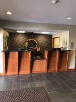 Una zona de recepción con un mostrador de madera, un espejo grande y una pared decorativa con motivos florales.