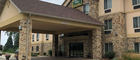 A hotel with a stone facade, a covered entrance, and a sign indicating it offers a country view, inns, and suites.