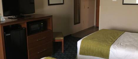 A hotel room with two beds, a television, a minibar, and a desk.