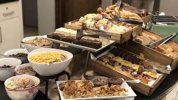 A buffet with various food items including cakes, pastries, and cereals.