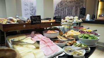 Un buffet con diverse pietanze, tra cui pasticcini, croissant e salumi.