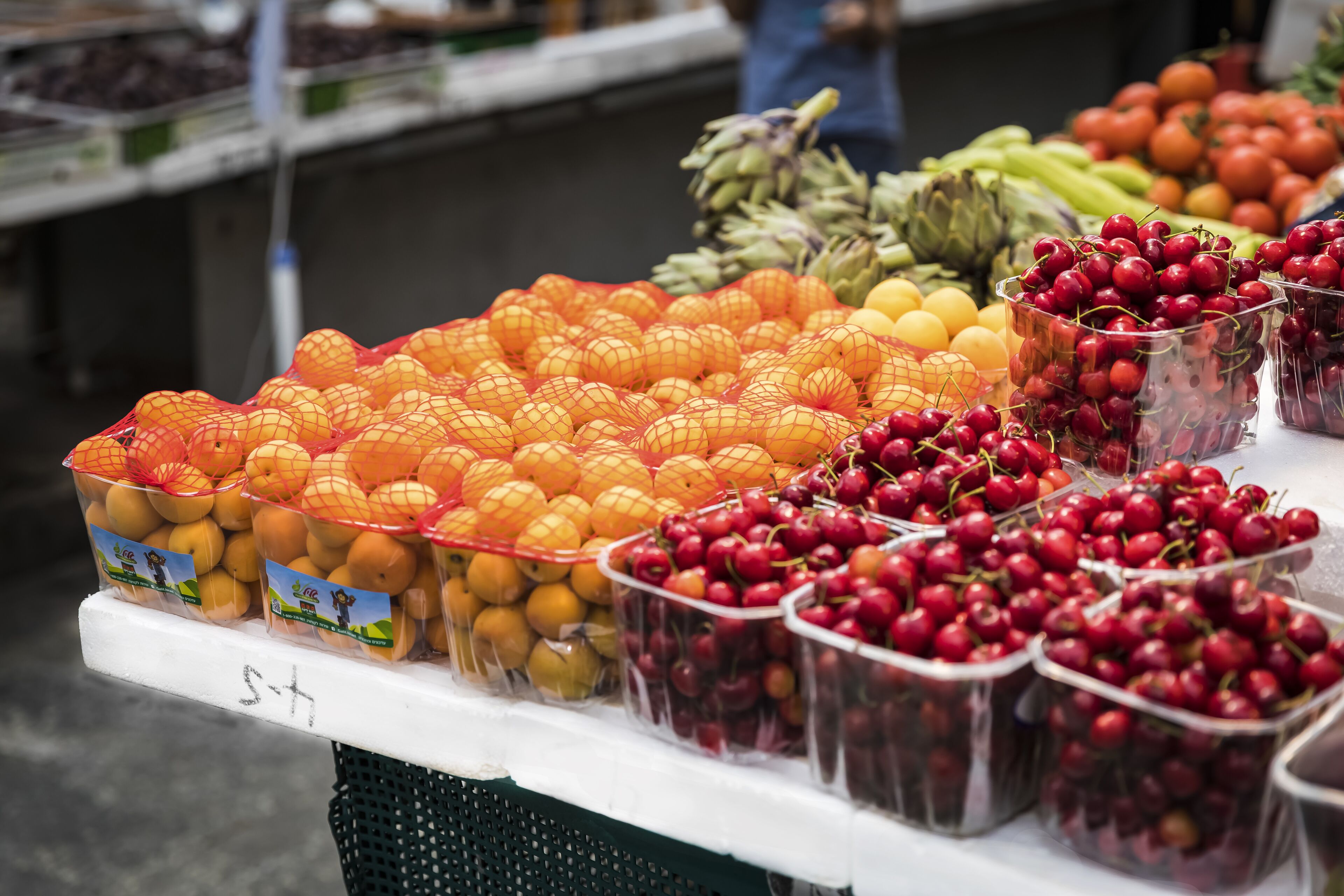 Un puesto de frutas con naranjas, limones y cerezas.
