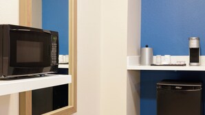 A microwave on a white shelf, a trash bin, and a coffee machine on a blue wall. - Holiday Inn Express & Suites Covington by IHG (Covington)
