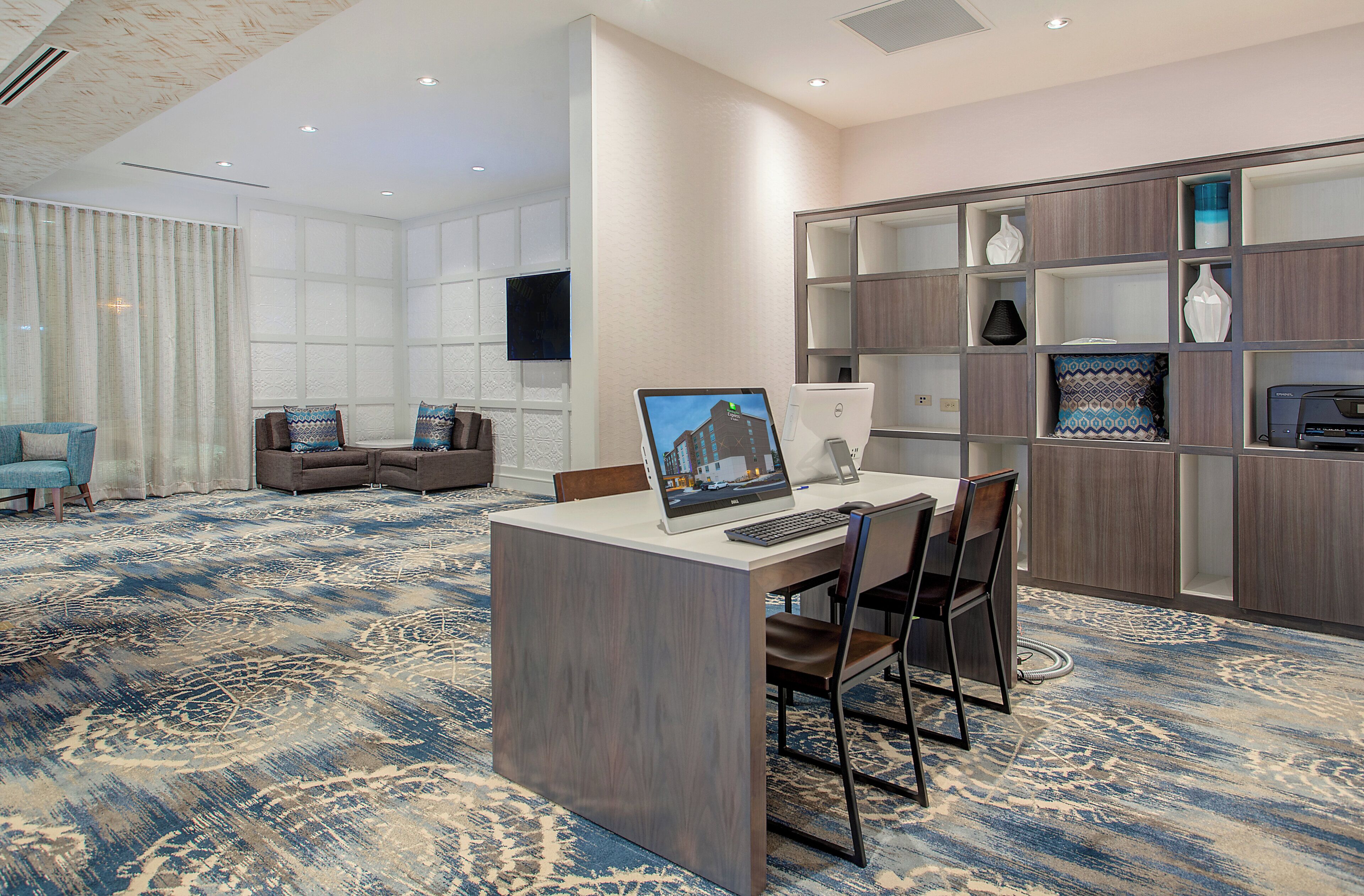 A hotel lobby with a reception desk, seating area, and a large window with curtains.