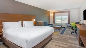 Quarto de hotel com cama grande, escrivaninha, cadeira e televisão.