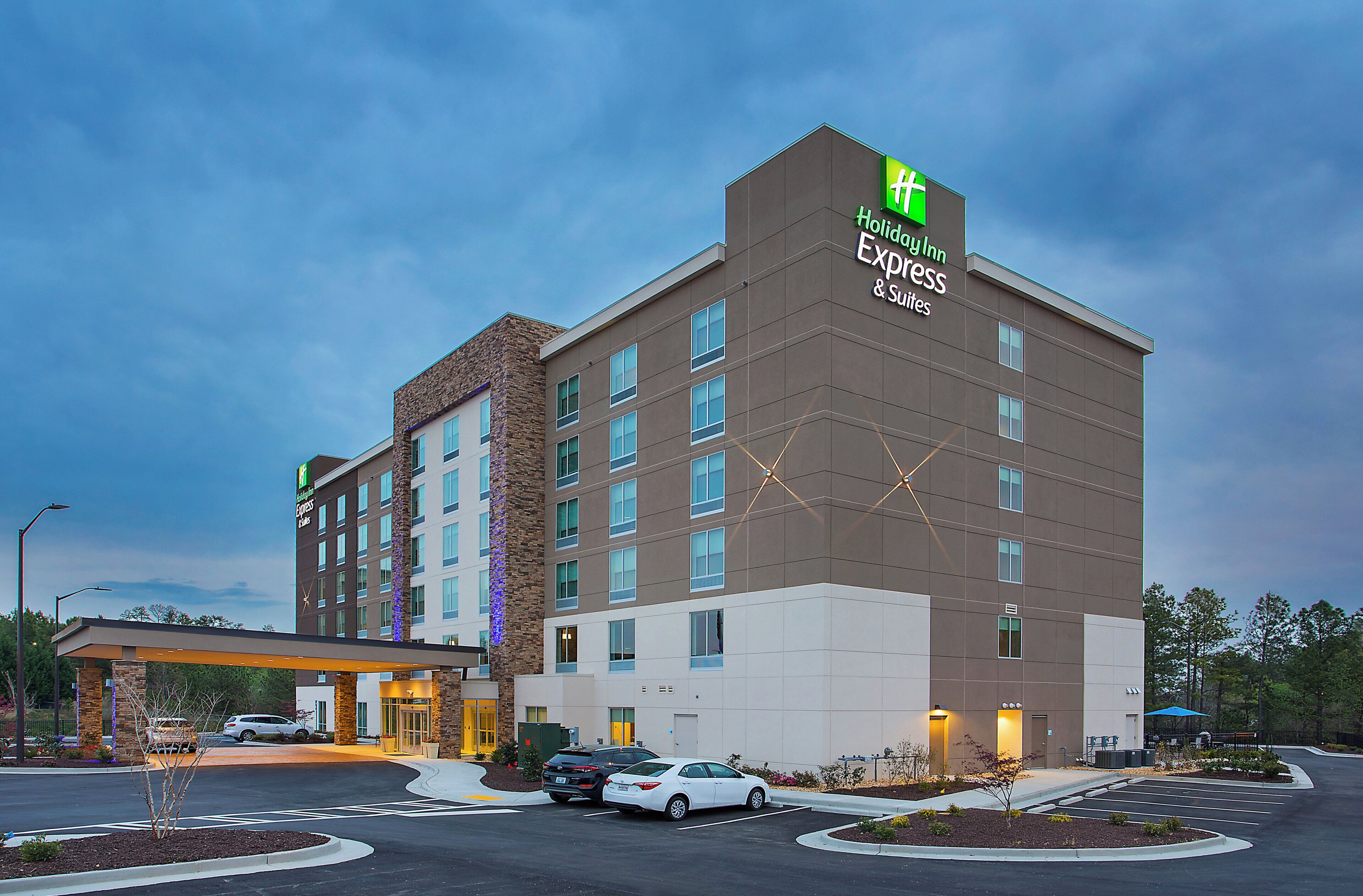 A hotel with a modern design, featuring a prominent sign for Holiday Inn Express & Suites.