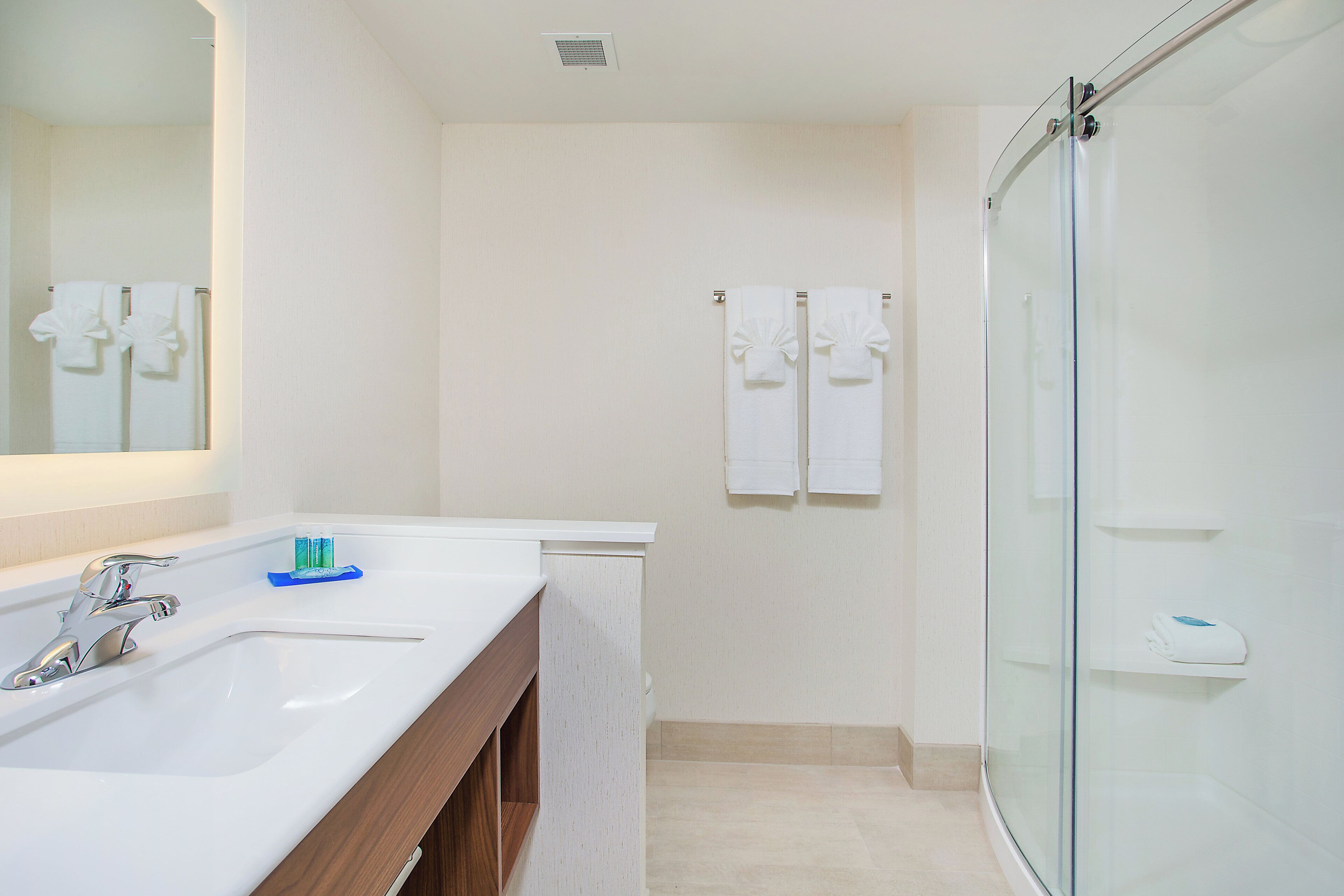 Un baño con lavamanos, espejo y ducha.