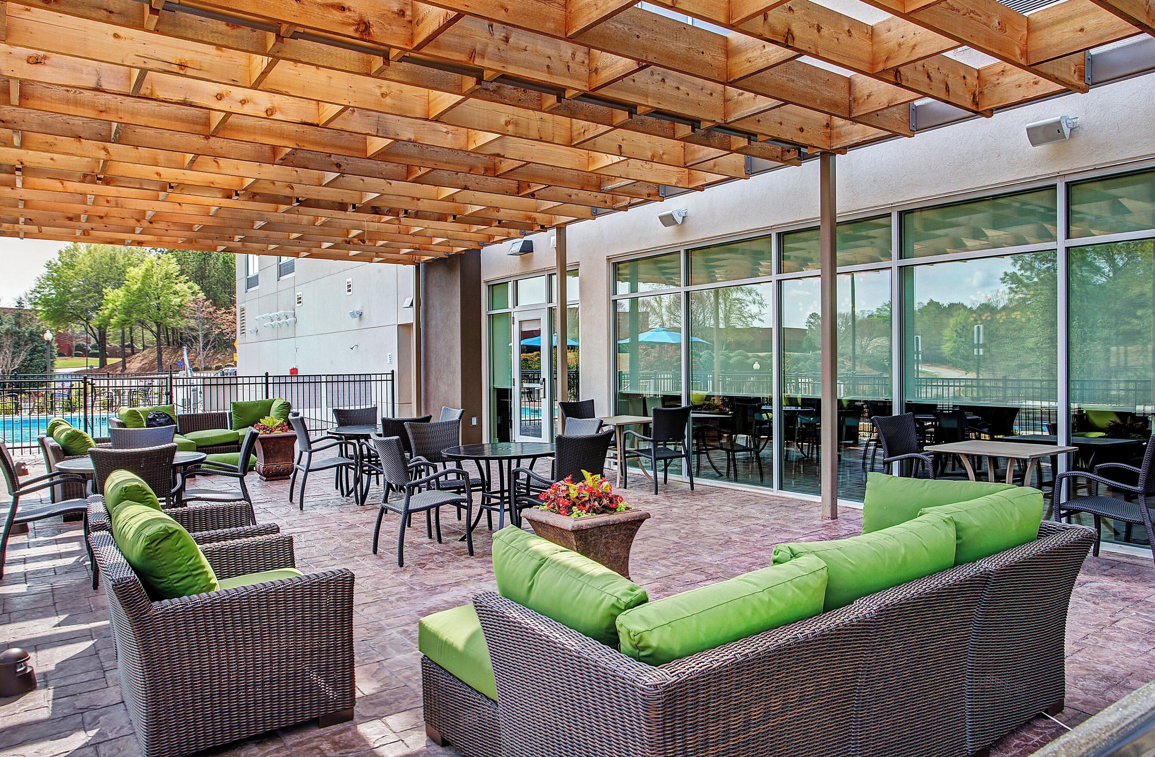 Un patio exterior con mobiliario de mimbre, una piscina y una zona de estar cubierta.