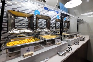 Buffet com seções de alimentos identificadas, incluindo omelete de queijo, biscoitos e outros itens.