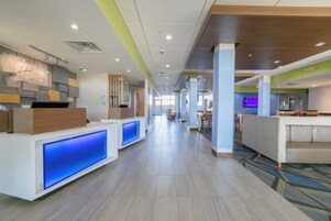 Um lobby de hotel moderno com balcão de recepção, área de estar e vista para o corredor.