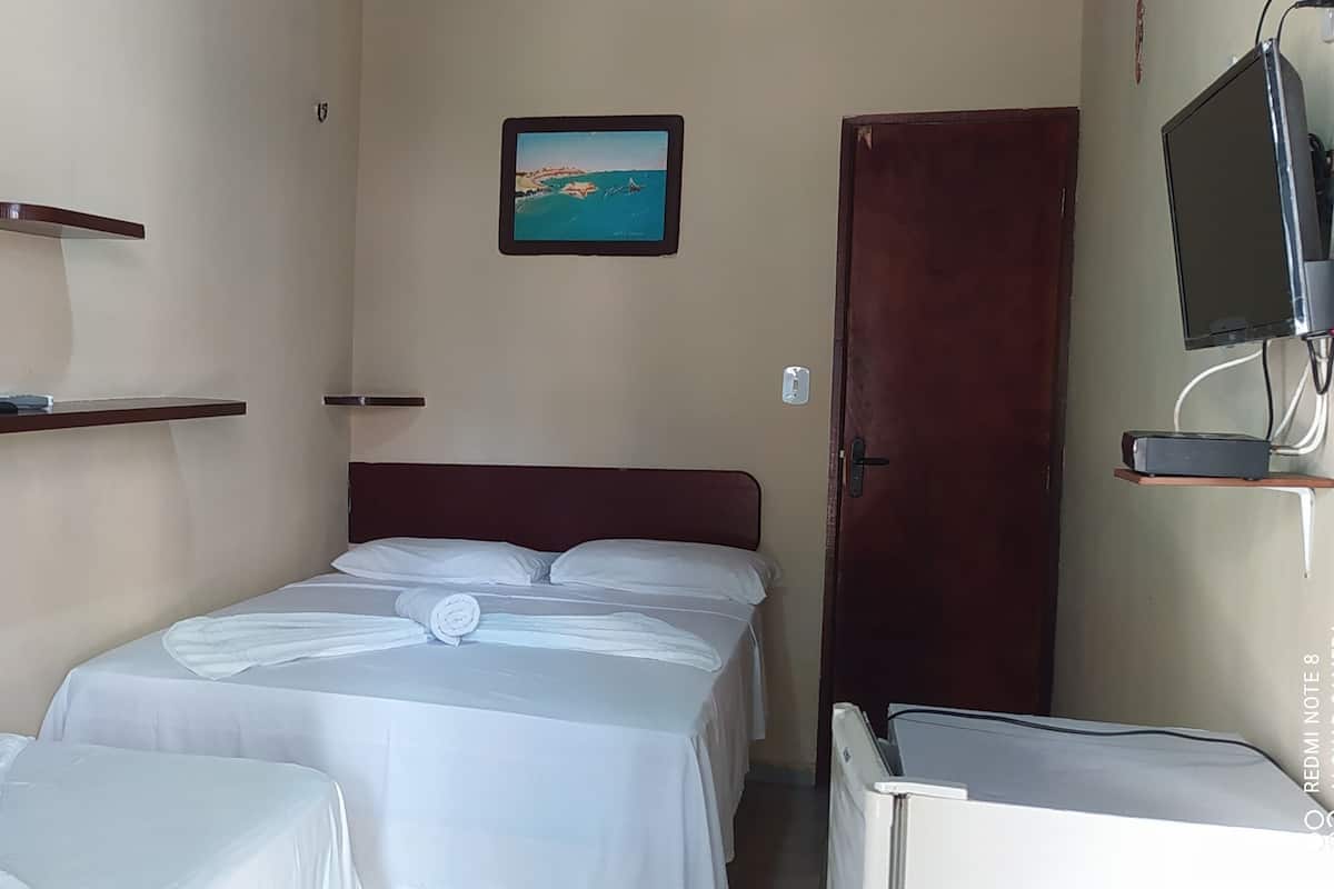 Une chambre d’hôtel avec deux lits, une télévision, un tableau et un bureau.