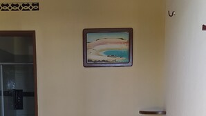 Una habitación de hotel con cama, un cuadro en la pared y la puerta del baño.