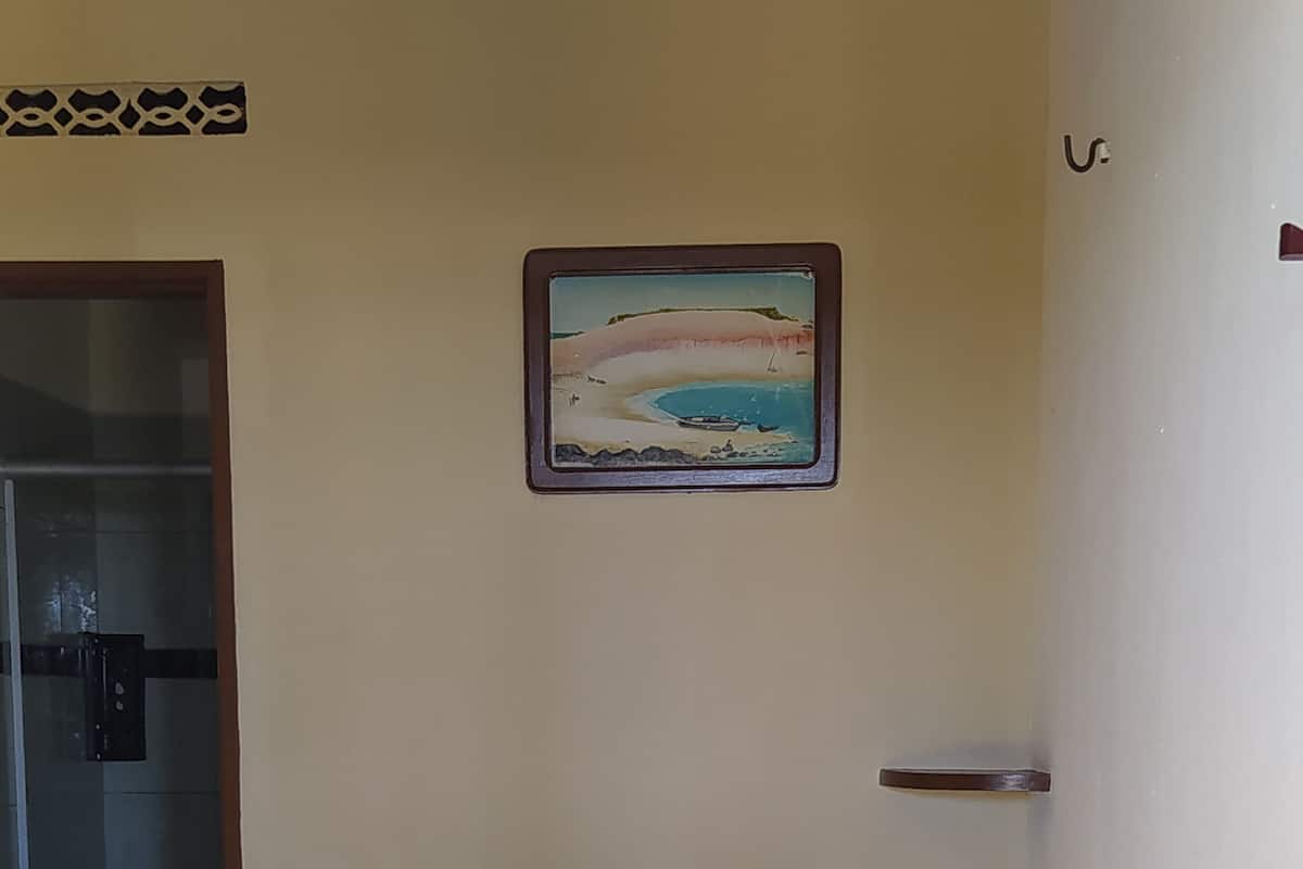 Une chambre d’hôtel avec un lit, un tableau au mur et une porte de salle de bain.