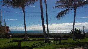 Zona verde con banco, palmeras y vista al océano.