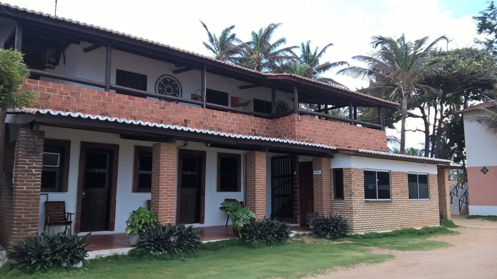 Un edificio de dos pisos con fachada de ladrillo, varias ventanas y un porche cubierto.
