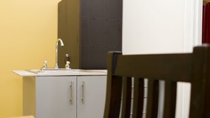 A kitchen with a sink, cabinets, and a chair. - Apartamento El Descanso (Curridabat)