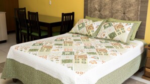 A neatly made bed with a quilt, a wooden headboard, and a green pillow. - Apartamento El Descanso (Curridabat)