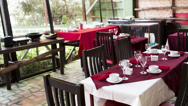 A restaurant with outdoor seating, red tablecloths, and white table settings. - Apartamento El Descanso (Curridabat)