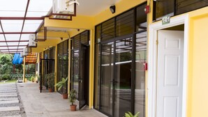 A building with a yellow facade, black sliding doors, and a white door marked with the number 1-01. - Apartamento El Descanso (Curridabat)
