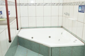 A bathroom with a bathtub, tiled walls, and a sign indicating a 15-minute wait for the jacuzzi. - Apartamento El Descanso (Curridabat)