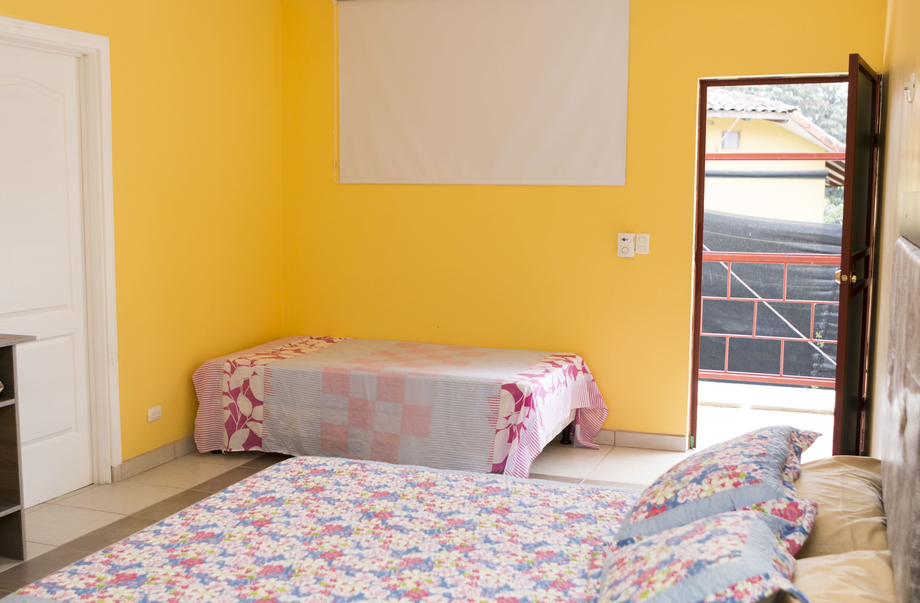 Une chambre avec deux lits, l’un recouvert d’une couvre-lit à motifs floraux et l’autre d’une couvre-lit à rayures.