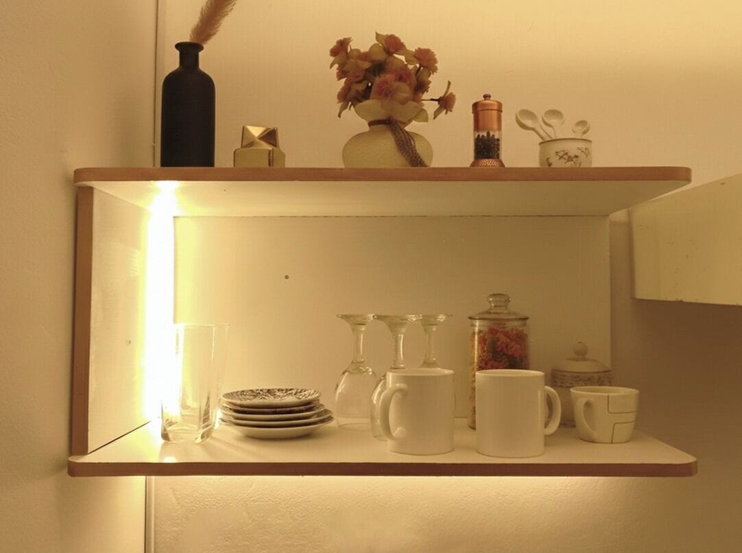 Una estantería con distintos utensilios de cocina, incluyendo platos, vasos y una cafetera.