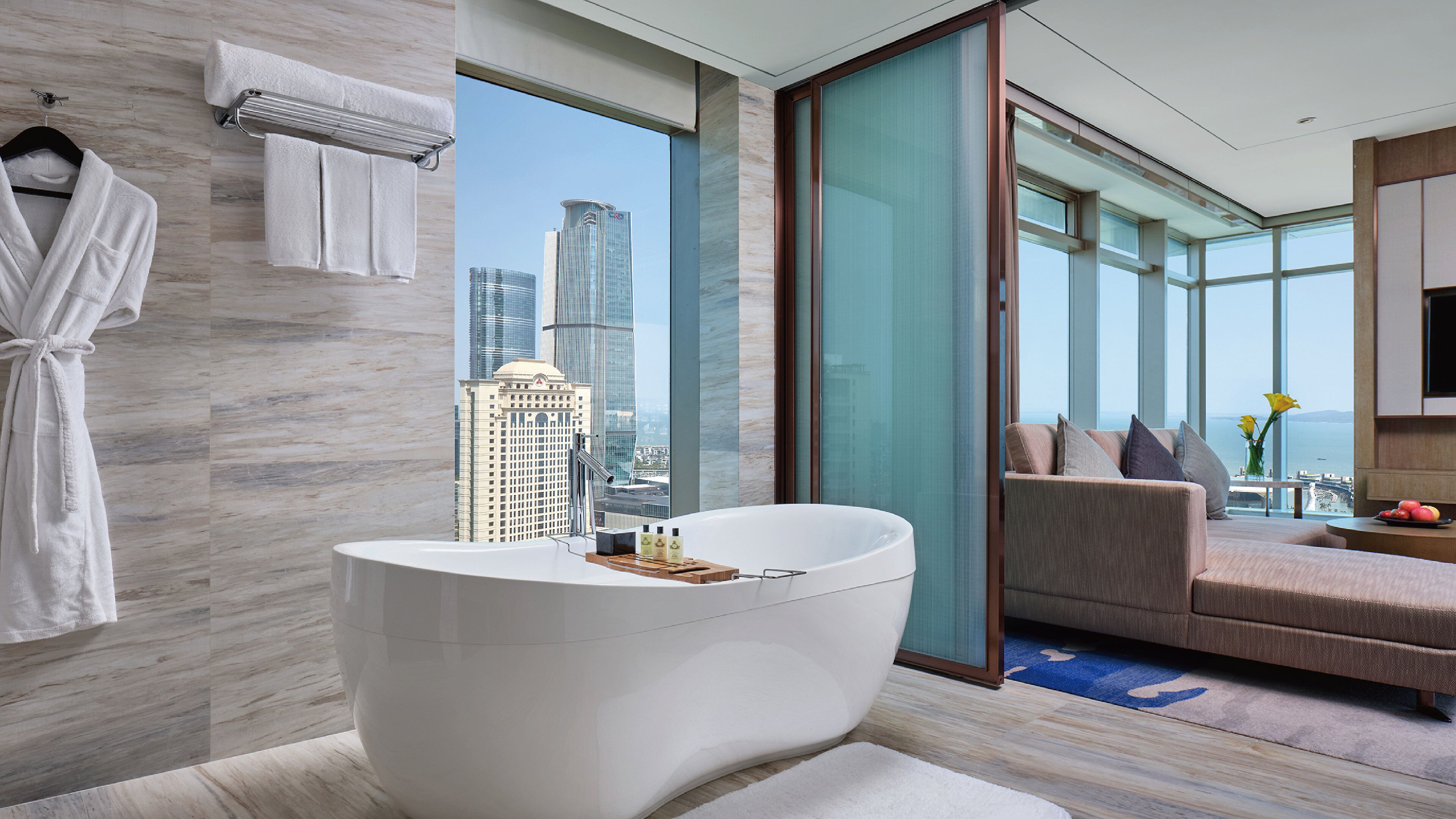 Un baño moderno con bañera, toallero y vistas a un paisaje urbano.