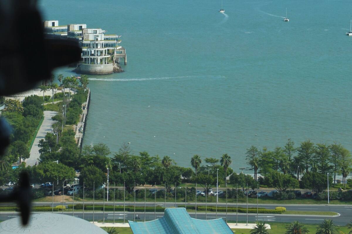 A coastal view with a marina, buildings, and a clear sky.