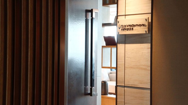 A wooden interior with a sliding door, a metal handle, and a sign with text. - Intercontinental Xiamen by IHG (Xiamen)