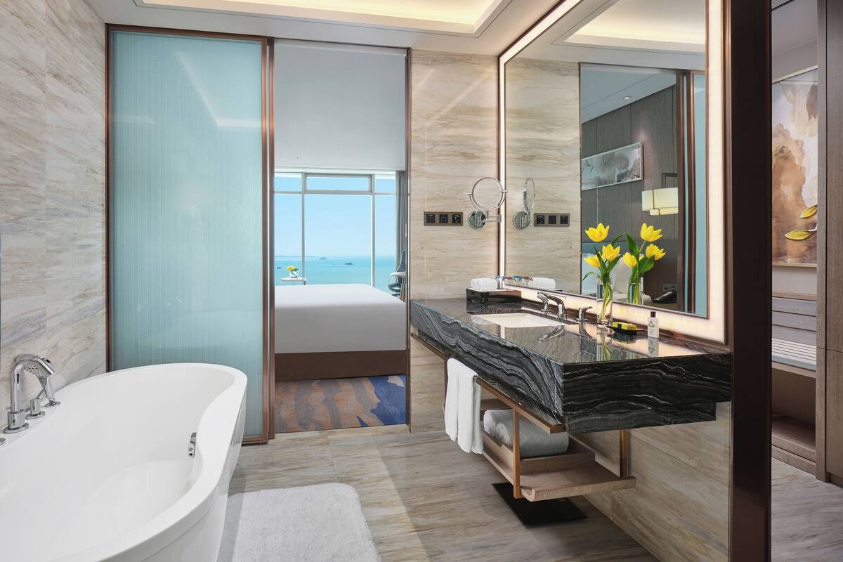 A modern bathroom with a large bathtub, dual sinks, and a large mirror.